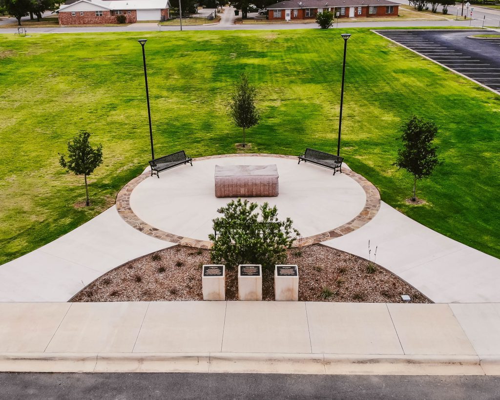 The Book natural stone sculpture and surrounding plaza at Abilene Christian University, featuring interpretive plaques, walkways, landscaping, and seating areas.